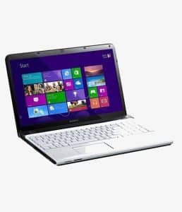 Professional studio photograph of a silver Sony Vaio laptop with water droplets on the screen and keyboard, next to a tipped-over glass of water, illustrating liquid damage repair services at Atlantis