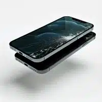 An iPhone 12 with a broken screen lying flat on a clean, white background.