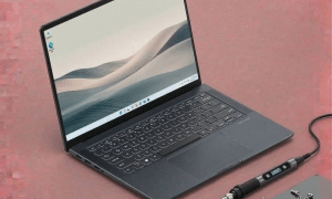 A professional technician performing component-level motherboard repair on an Asus ZenBook using a micro-soldering station, shown on a solid light pink background for Atlantis UK-wide services.