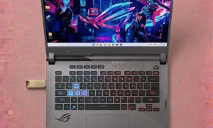 A professional micro-soldering repair of an Asus ROG gaming laptop USB 3.2 port, displayed on a solid light pink background for Atlantis Canterbury and UK-wide repair services.