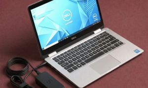 Close-up of a high-quality replacement internal DC power jack with a reinforced charging port and cable for a Dell laptop, positioned on a solid light pink background for Atlantis repair services.