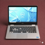 A premium replacement backlit QWERTY keyboard assembly for a Dell laptop, shown on a solid light pink background for Atlantis repair services.