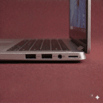 A close-up of a high-quality replacement internal USB-C and USB 3.0 port assembly for a Dell laptop motherboard, positioned on a solid light pink background for Atlantis repair services.