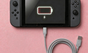 A premium replacement 12-pin USB-C charging port connector for a Nintendo Switch, displayed on a solid light pink background for Atlantis UK-wide console repair services.