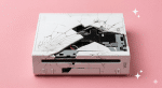 A premium high-gloss white replacement outer shell housing for a Nintendo Wii console, displayed on a solid light pink background for Atlantis UK-wide restoration services.