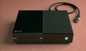 Close-up of a high-precision replacement HDMI socket for the Xbox One, One S, and One X consoles, positioned on a solid light pink background for Atlantis repair services.