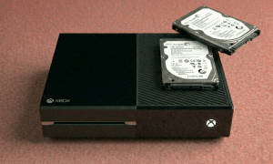 Close-up of a high-performance internal 1TB or 2TB SATA replacement hard drive for the Xbox One, One S, and One X, positioned on a solid light pink background for Atlantis repair services.