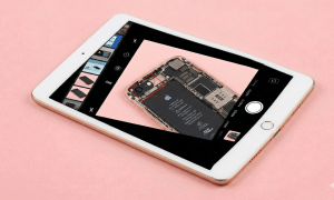 A high-quality replacement 8MP rear-facing camera module for an iPad 6th, 7th, 8th, or 9th generation, shown on a solid light pink background for Atlantis repair services.