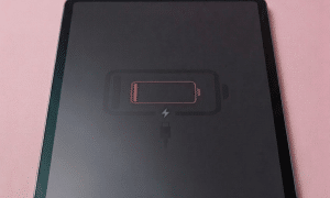 A premium replacement USB-C charging port and high-speed data dock connector for an iPad Pro 11-inch and 12.9-inch, shown on a solid light pink background for Atlantis repair services.