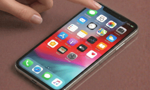 Close-up of a replacement front-facing camera module and TrueDepth sensor assembly for the iPhone 11, positioned on a solid light pink background for Atlantis repair services.