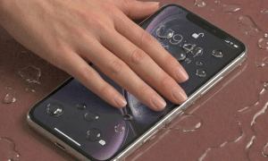 Detailed internal view of an iPhone 11 logic board showing specialist corrosion removal and ultrasonic cleaning, positioned on a solid light pink background for Atlantis repair services.