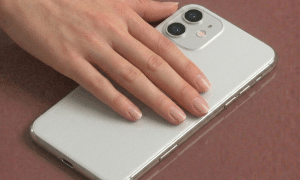 Close-up of precision-cut sapphire glass replacement rear camera lenses for the iPhone 11, 11 Pro, and 11 Pro Max, shown on a solid light pink background for Atlantis repair services.