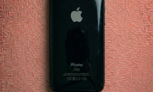 A brand new black and white replacement rear housing shell for the iPhone 3G and 3GS, showing the iconic curved gloss finish, positioned on a solid light pink background for Atlantis repair services.