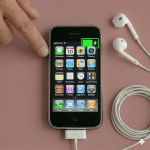 Close-up of a replacement 30-pin charging port and dock connector assembly for the iPhone 3G and 3GS, positioned on a solid light pink background for Atlantis repair services.