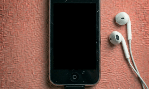 Close-up of a replacement headphone jack flex cable assembly for the iPhone 3G and 3GS, including the volume and mute switch contacts, on a solid light pink background for Atlantis.