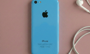 Close-up of the rear aluminium housing and glass panels of an Apple iPhone 5S, positioned on a solid light pink background for Atlantis repair services.