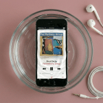 Close-up of an Apple iPhone 5S being treated for liquid exposure, showing the internal components on a solid light pink background for Atlantis repair services.