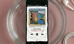 Close-up of an Apple iPhone 5S being treated for liquid exposure, showing the internal components on a solid light pink background for Atlantis repair services.