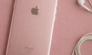 Close-up of the rear aluminium unibody and frame of an Apple iPhone 6 and 6S series handset, set against a solid light pink background for Atlantis repair services.