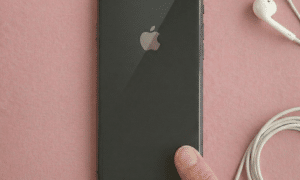 Close-up of the dual rear camera lens module on an Apple iPhone 7 Plus and 8 Plus, positioned on a solid light pink background for Atlantis repair services.