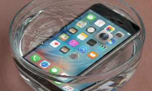 Detailed view of an iPhone 7, 8, and SE logic board undergoing specialist ultrasonic cleaning and corrosion removal, positioned on a solid light pink background for Atlantis repair services.