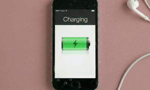 Close-up of a high-capacity internal lithium-ion replacement battery for an iPhone, positioned on a solid light pink background for Atlantis repair services.