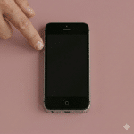 Close-up of the volume control buttons on the side of an iPhone, positioned on a solid light pink background for Atlantis repair services.