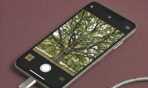 Close-up of a high-resolution replacement dual-lens camera module for the iPhone X and XS, and the single-lens sensor for the iPhone XR, on a solid light pink background for Atlantis repair services.