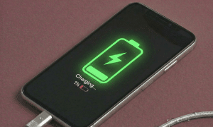 Close-up of a replacement Lightning charging port and microphone flex cable assembly for the iPhone X, XR, and XS series, positioned on a solid light pink background for Atlantis repair services.