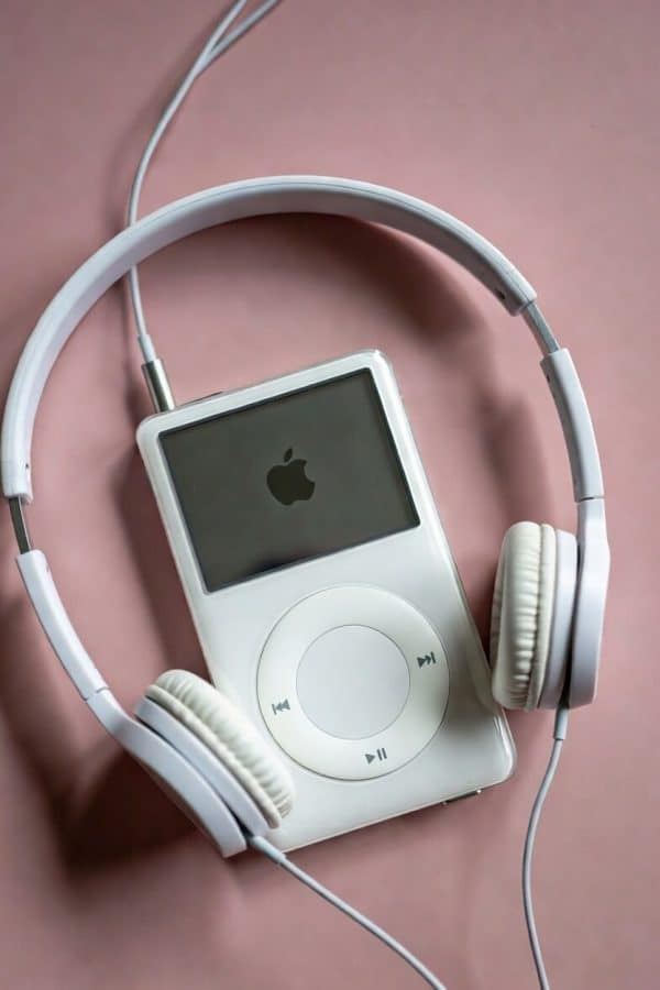 Professional 1:1 square studio photograph of the top profile of a silver Apple iPod Classic, focusing on the headphone jack socket against a solid light pink background for Atlantis repair services.