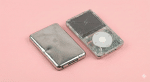 High-quality studio photograph showing a damaged silver Apple iPod Classic with a heavily scratched and dented metal back panel next to a cracked front casing, isolated on a light pink background for Atlantis repair services.