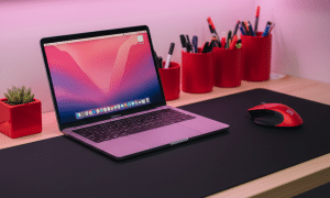 Professional laptop repair desk setup with black mat, red mouse, and boutique pink LED lighting.