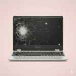 Professional 1:1 square studio photograph of a silver Lenovo laptop featuring a heavily cracked and shattered screen, set against a solid light pink background for Atlantis laptop screen repair services.