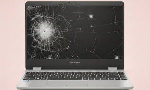Professional 1:1 square studio photograph of a silver Lenovo laptop featuring a heavily cracked and shattered screen, set against a solid light pink background for Atlantis laptop screen repair services.