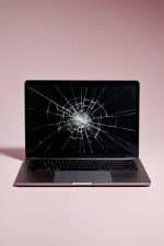 Professional front-facing view of a MacBook Pro with a severely cracked and shattered Retina display, isolated on a clean studio background to illustrate professional screen replacement services.