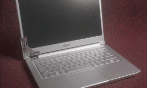 A close-up of a high-torque steel hinge being professionally realigned and anchored into an Acer laptop chassis, shown on a solid light pink background for Atlantis repair services.