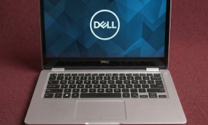 A professional technician performing a comprehensive hardware diagnostic and multi-point health check on a Dell laptop motherboard, shown on a solid light pink background for Atlantis repair services.