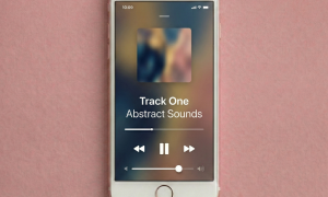 Close-up of the rear camera lens and bottom speaker grilles on an Apple iPhone 7 and 8 Plus, set against a solid light pink background for Atlantis repair services.