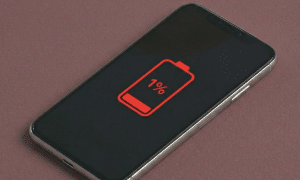 Close-up of a high-quality replacement lithium-ion battery with a precision connector for the iPhone X, XR, and XS series, positioned on a solid light pink background for Atlantis repair services.