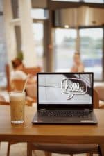 shallow focus photo of black laptop computer and glass of coffee on wooden table
